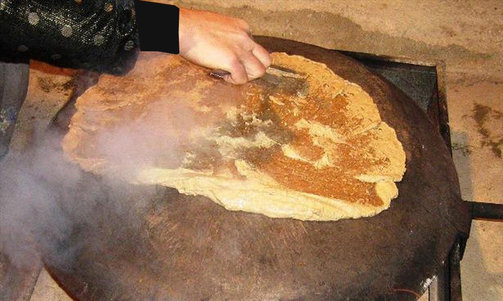 This bread is one of the oldest local breads in Kohgiluyeh and Boyer Ahmad provinces, and it is made from oak sap. To prepare this bread, they remove the outer shell of the acorn, and after leaving it to dry for a time, they remove the inner film surrounding the acorn, which is used to treat stomach aches. Then, they soak the acorns in water for a week to make a paste and refine it in baskets made of mountain almonds. After refining, they knead it by hand and spread it on a baking sheet with a tool called “Hasum”. They put it on the baking sheet until both sides of the bread are toasted and brown. Image – Soraya Heydari